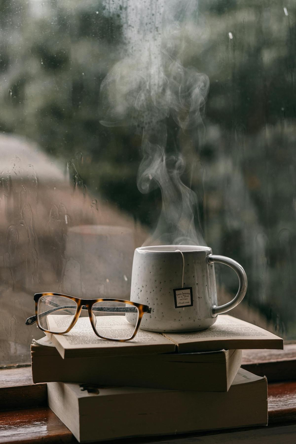 steaming hot cup of tea by a rainy window